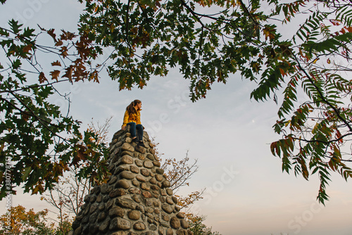 Girl perched on a monument looking at the moon photo