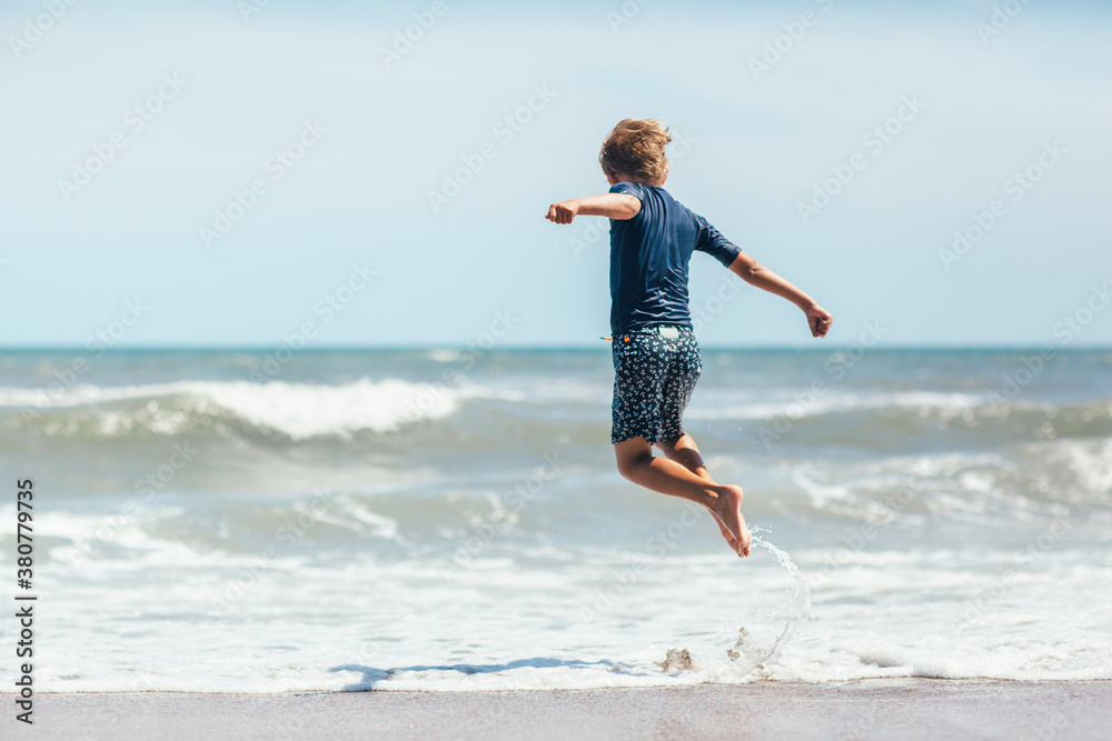 child jumping over ocean wave child jumping over ocean wave
