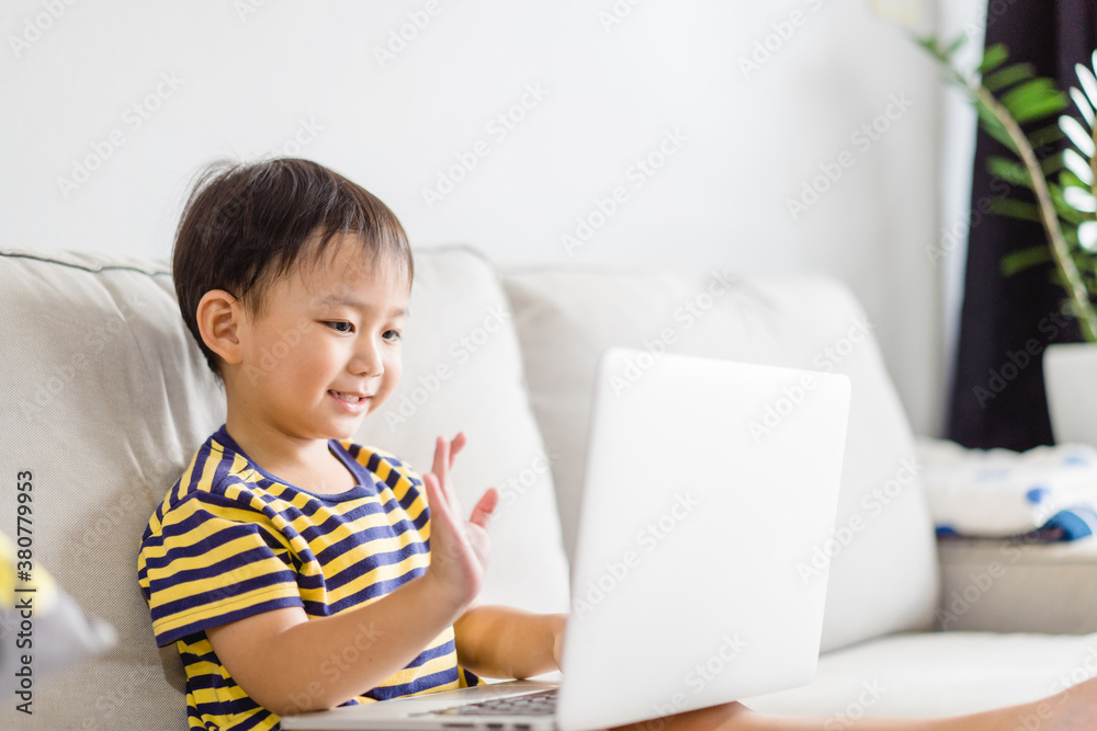 Asian toddler boy student study online learning online education video call zoom teacher.Happy boy learn english online with laptop at home.New normal.Covid-19 coronavirus.Social distancing.stay home.