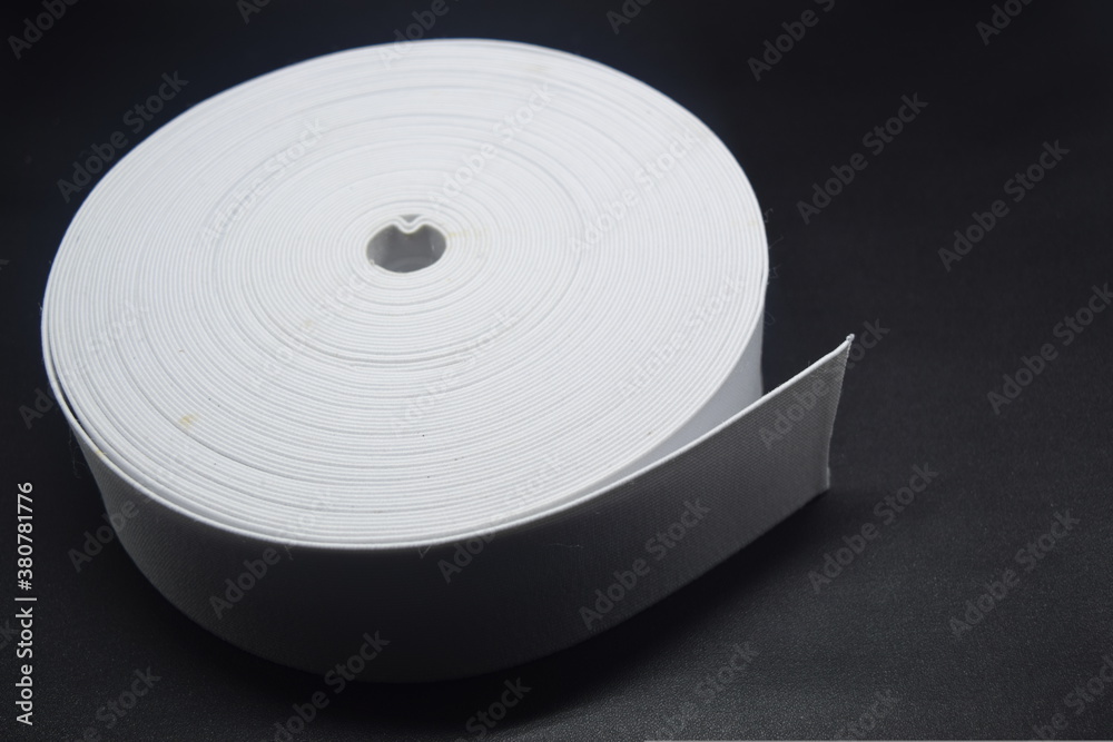 Rubber roll. White elastic band roll for sewing close-up. Fabric tape for needlework of the cloth on black background. Rubber roll. White elastic band roll for sewing close-up. Fabric tape for needlework of the cloth on black background.