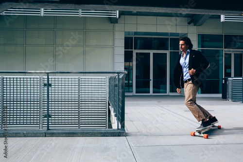 Young businessman going to work on a skateboard photo