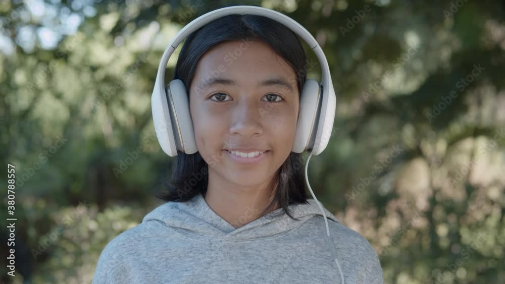 Medium close up of Asian woman happy and smile listening to music on headphones in park Medium close up of Asian woman happy and smile listening to music on headphones in park