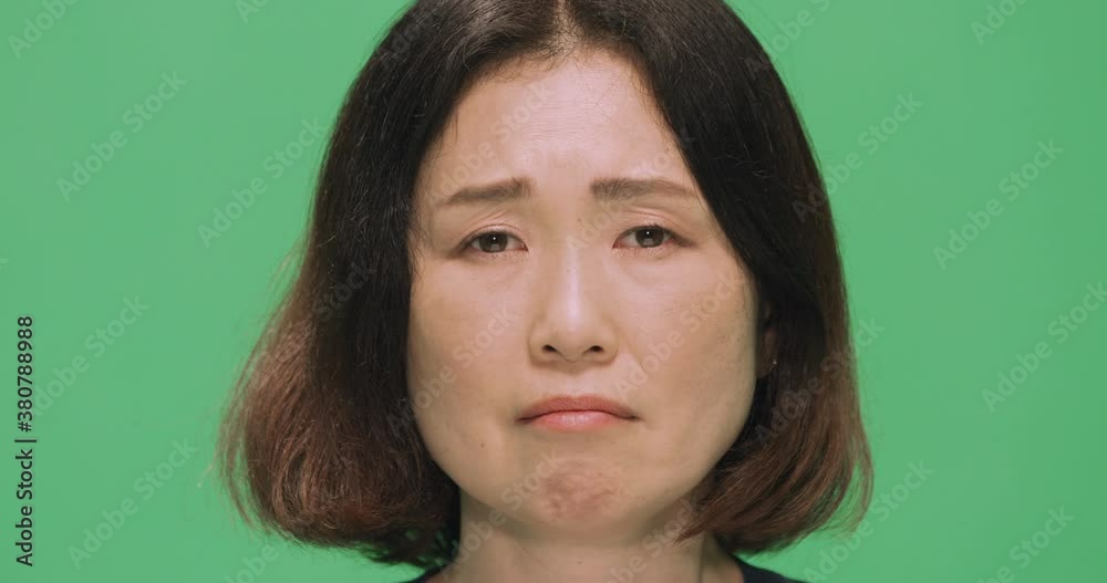 Studio, slow motion, a portrait of a sad Japanese woman against a green screen, London, UK Studio, slow motion, a portrait of a sad Japanese woman against a green screen, London, UK