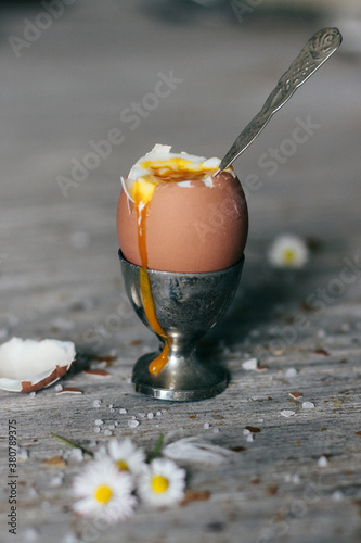broken boiled egg in silver eggcup on wooden board