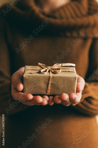 Woman holding small brown present box in her hand