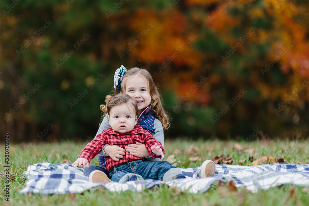 Young girl and toddler laying on a blanket outside Young girl and toddler laying on a blanket outside