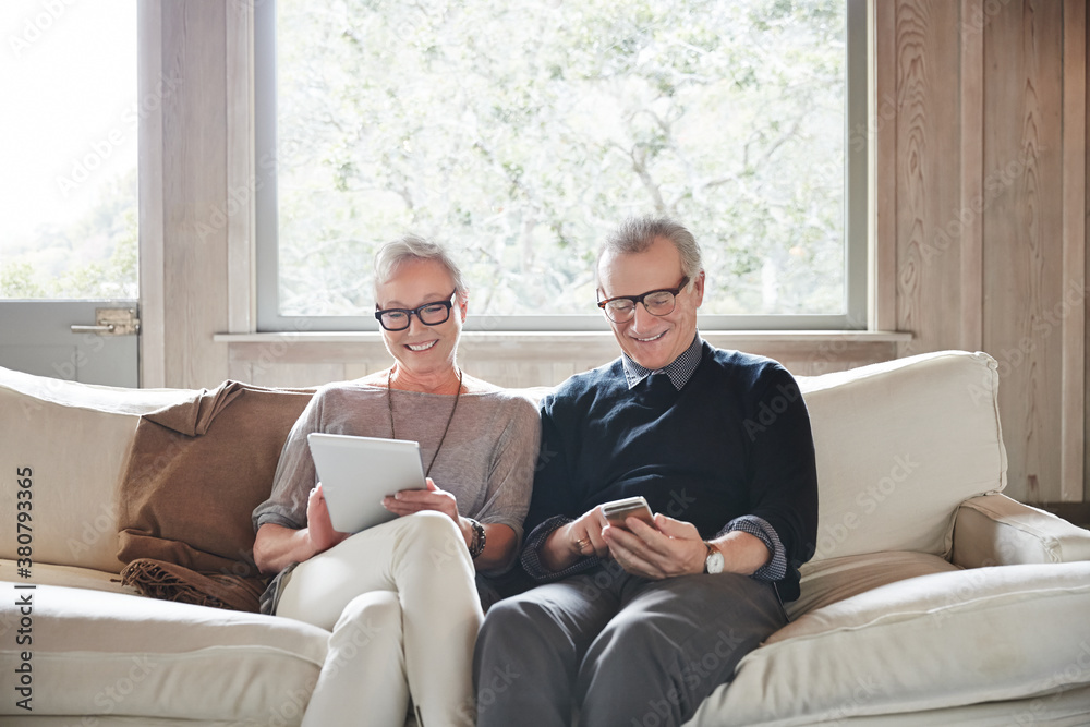 Mature couple with grey hair looking at digital tablet and phone at home Mature couple with grey hair looking at digital tablet and phone at home