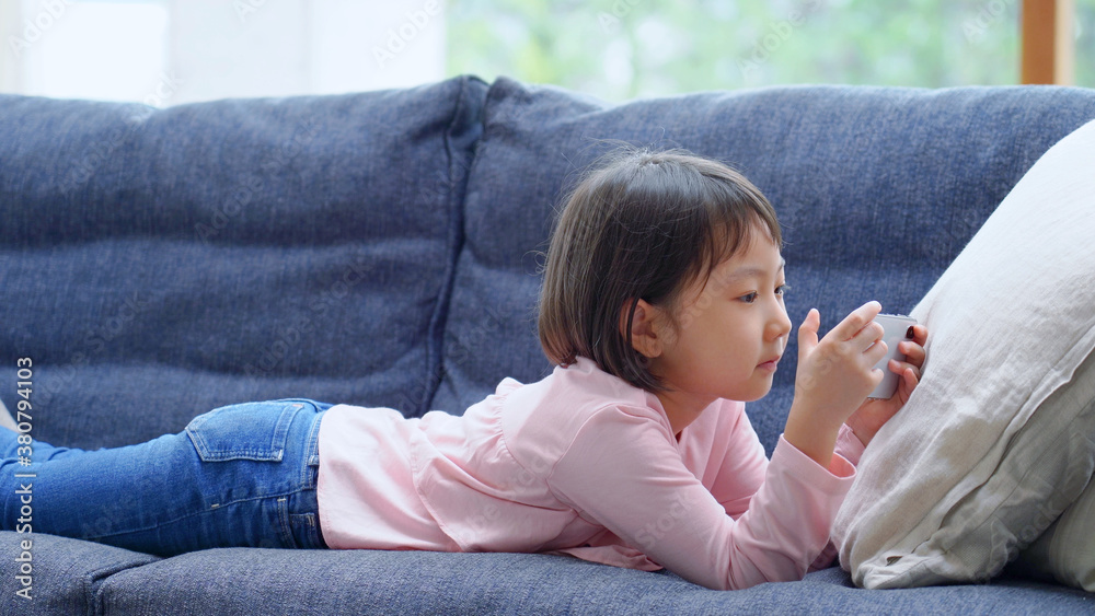 ソファーでスマートフォンを使う女の子 ソファーでスマートフォンを使う女の子