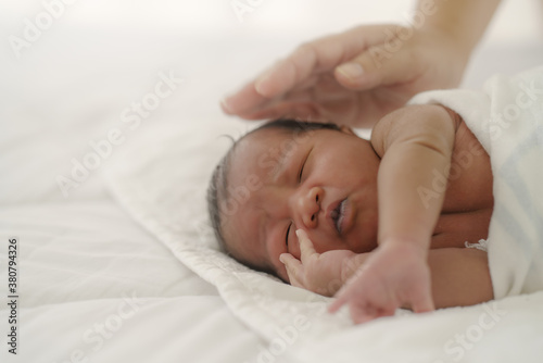 african american new born baby lying on white bed