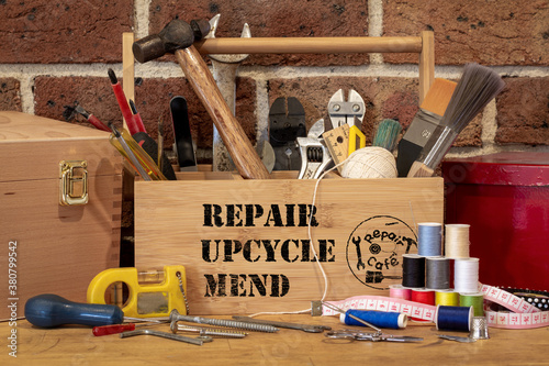 tool box with repair, upcycle, mend stencil text surrounded by repair tools on bench, consumer activism to repair household items to reduce waste and support a sustainable lifestyle photo