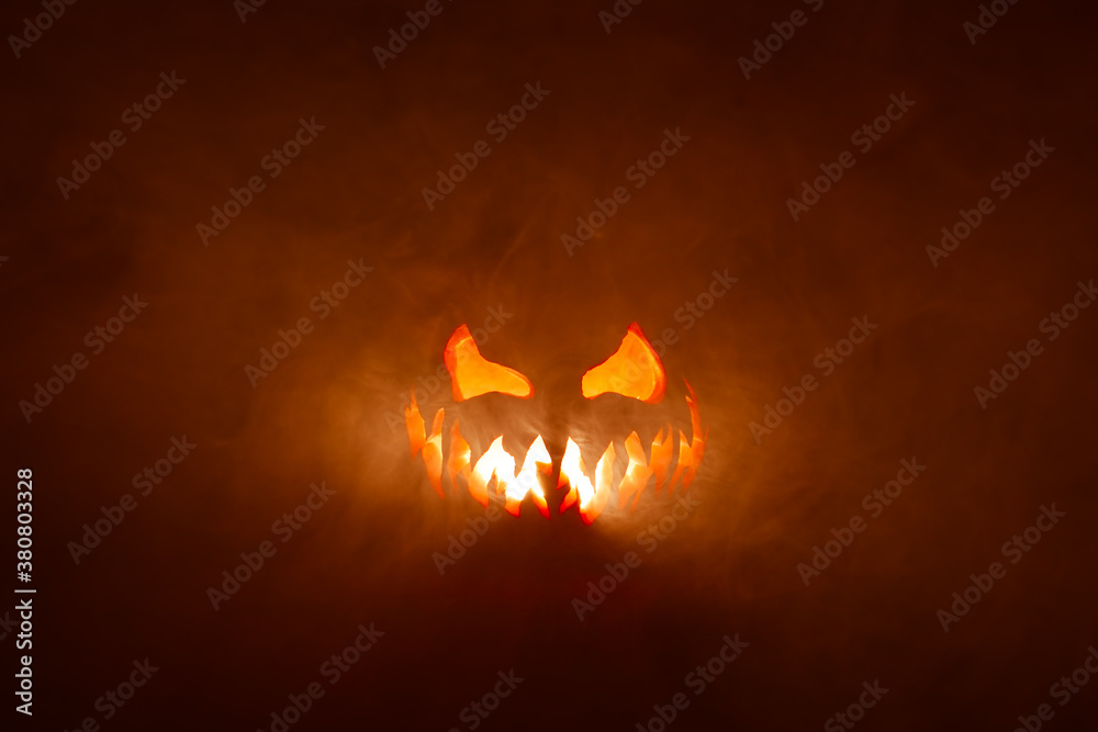 Scary Halloween jack o lantern face glowing in smoke and fire. - obrazy, fototapety, plakaty 