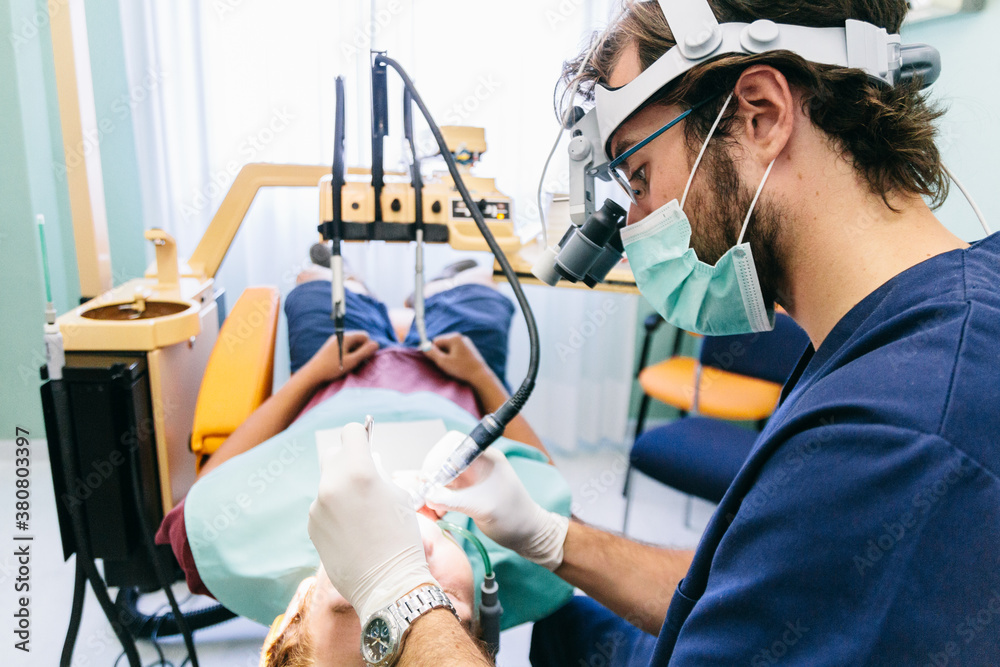Dentist with microscope glasses during a root canal intervention Stock