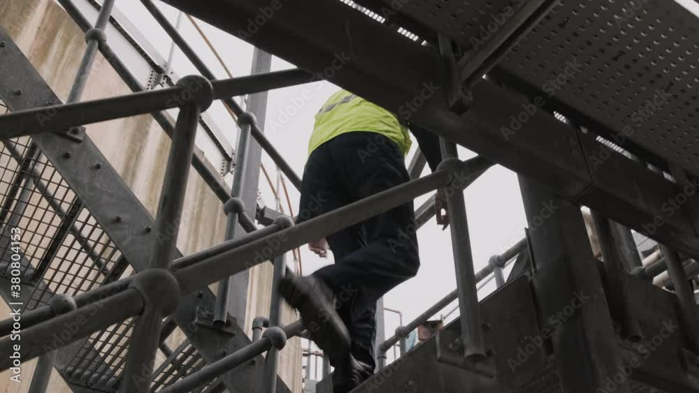 Industrial worker walking up stairs on industrial site wearing protective workwear