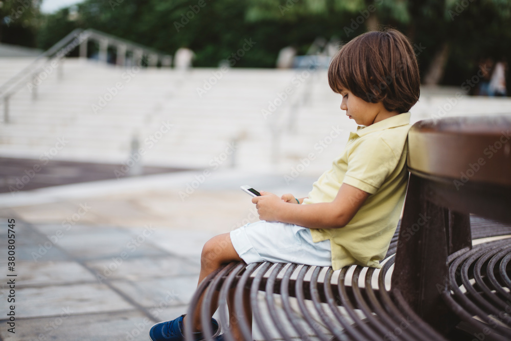 5 year old boy using a smartphone outdoor