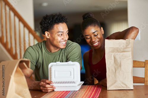 african american couple sitting at table looking at food delivery
