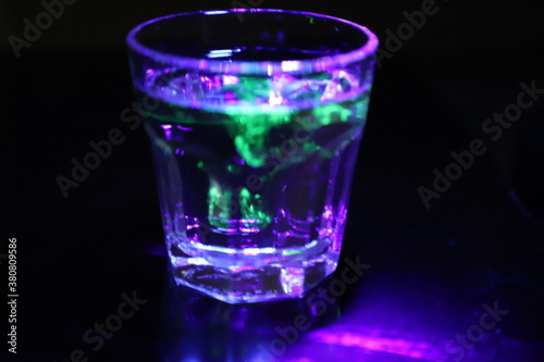 A Glass with a Glowing Green and Yellow Liquid Swirling Around Inside