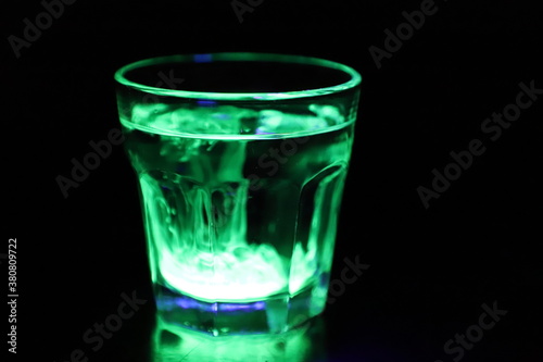 A Glass with a Glowing Green and Yellow Liquid Swirling Around Inside