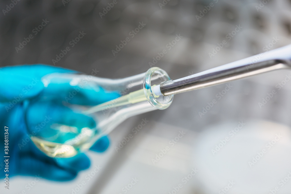 Chemist taking probe from test tube with pipette Chemist taking probe from test tube with pipette