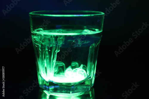 A Glass with a Glowing Green and Yellow Liquid Swirling Around Inside