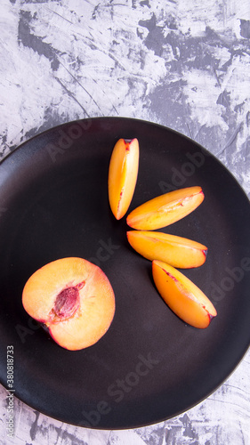 Plum whole and sliced on a black plate photo