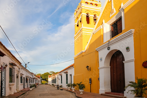 Typical street with one story buildings in sun and shadow and yellow church,  Santa Cruz de Mompox, Colombia, World Heritage photo