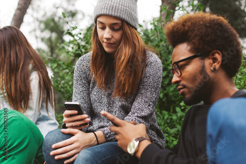 Group of friends chatting with their smartphones.