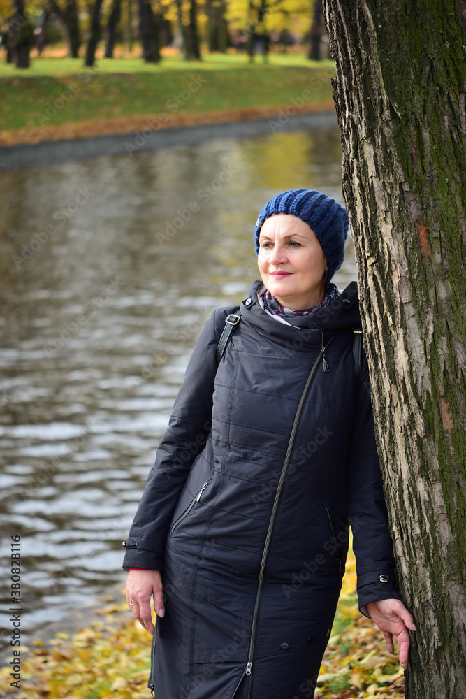 An attractive middle-aged woman dressed in casual clothes walks in an autumn park. An attractive middle-aged woman dressed in casual clothes walks in an autumn park.