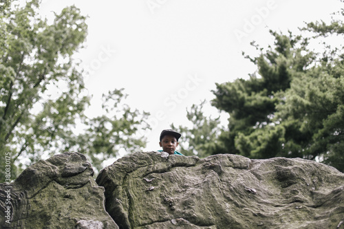 Young african american boy sticking his head out on top of a rock photo