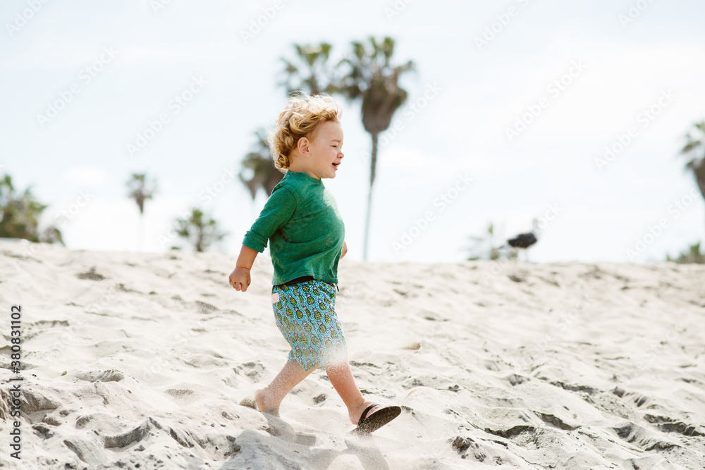 Curly blonde haired toddler running on a California beach Curly blonde haired toddler running on a California beach