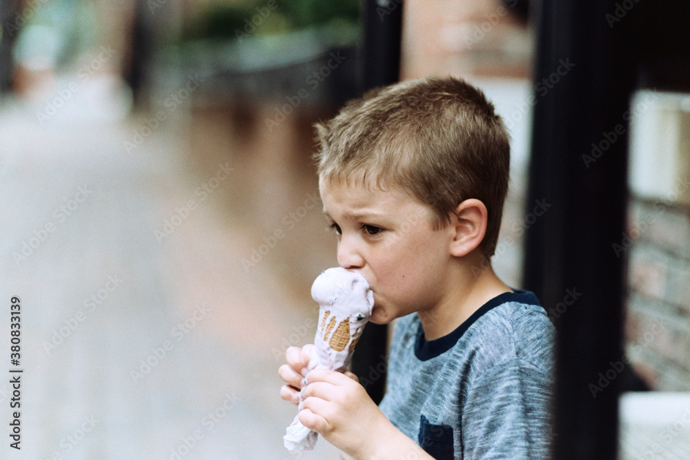 Young boy taking a bite of quickly melting ice cream Young boy taking a bite of quickly melting ice cream