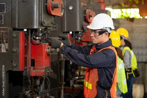 Technician engineer wearing hard hat and safety glasses maintenance the machine in the factory. Industry worker control machines in the workplace on a business day. Concept of Industrial manufacturing