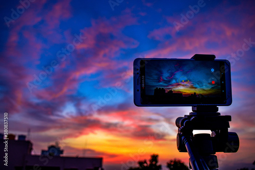 A mobile is placed on a tripod stand with a beautiful view on the sky behind. Reddish blue evening sky