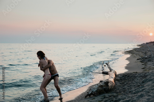 Couple playing on the beach who is stronger to push the other first into the water