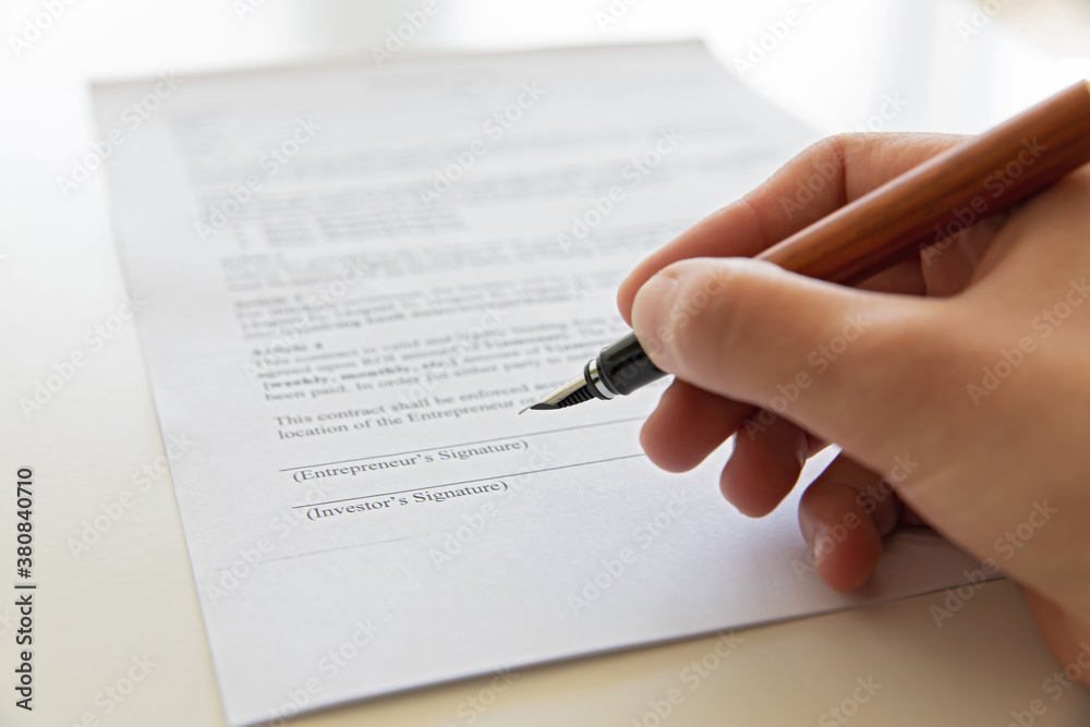 Close up of hand signing document.