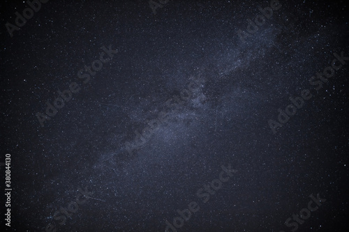 in a night sky you can see the milky way and the traces of satellites