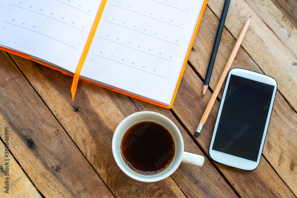 notebook planner ,mobile phone and hot coffee for business work of lifestyle arrangement flat lay style on background wooden notebook planner ,mobile phone and hot coffee for business work of lifestyle arrangement flat lay style on background wooden