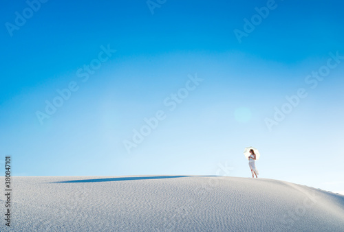 Woman on Sand Dune with Sun Umbrella In White Sands National Monumant New Mexico & Vibrant Blue Sky photo