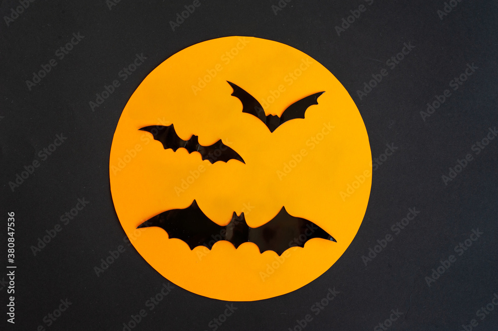 Halloween. Composition. Black bats and spiders against the orange moon and black background.