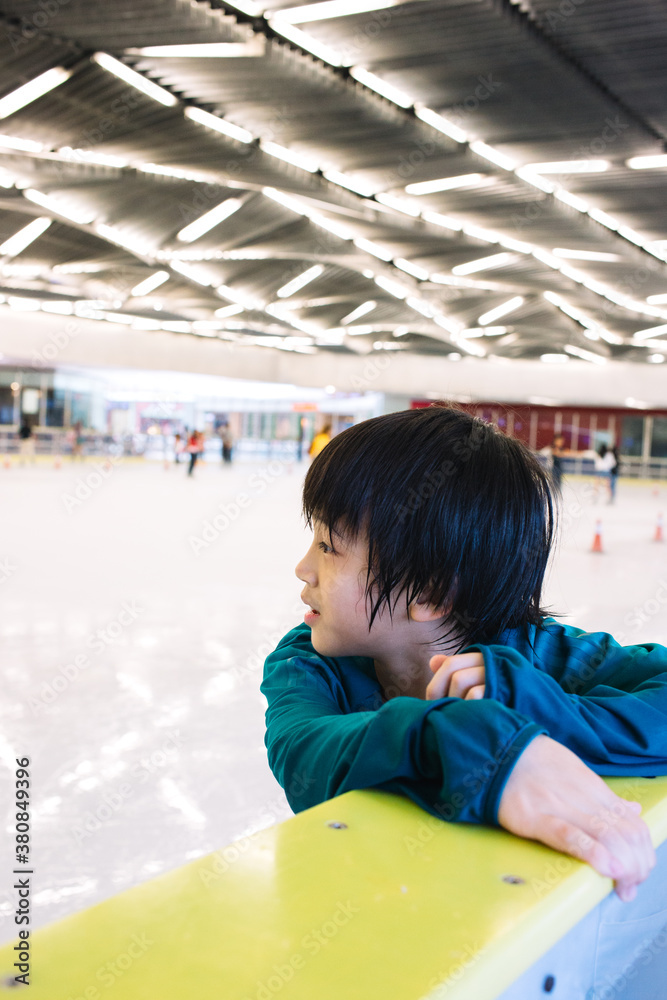 Young boy sweating from too much ice skating rests on the guard railing Young boy sweating from too much ice skating rests on the guard railing