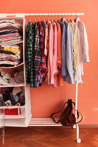 Colorful shirts and other clothes on hangers in girly room photo