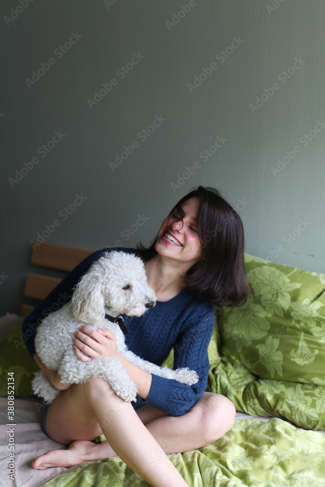 Beautiful happy woman playing with her dog on the bed Beautiful happy woman playing with her dog on the bed