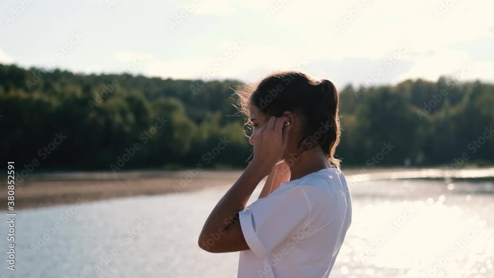 A woman in headphones runs at a beautiful sunset on the beach, sun glare from the water. Sport and healthy lifestyle concept A woman in headphones runs at a beautiful sunset on the beach, sun glare from the water. Sport and healthy lifestyle concept