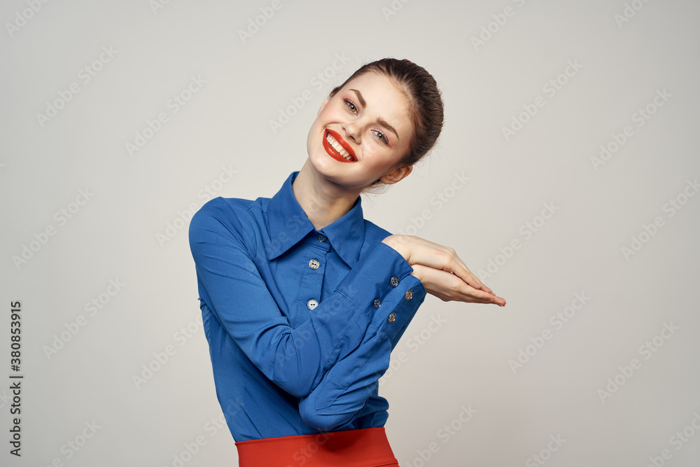 An elegant lady in a blue shirt is gesturing with her hands on a light background and a copy space close-up portrait