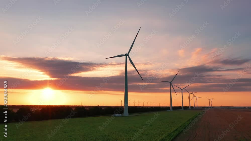 Aerial view of wind turbines standing in sunset. Aerial View of a Farm With Wind Turbines. Generating Clean Renewable Energy. bright orange sunset wind park slow motion drone. Alternative energy Aerial view of wind turbines standing in sunset. Aerial View of a Farm With Wind Turbines. Generating Clean Renewable Energy. bright orange sunset wind park slow motion drone. Alternative energy