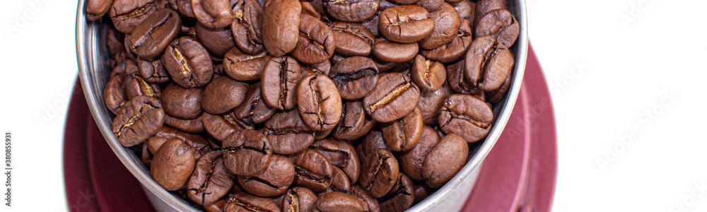 A lot of coffee beans in a metal coffee grinder on a white background