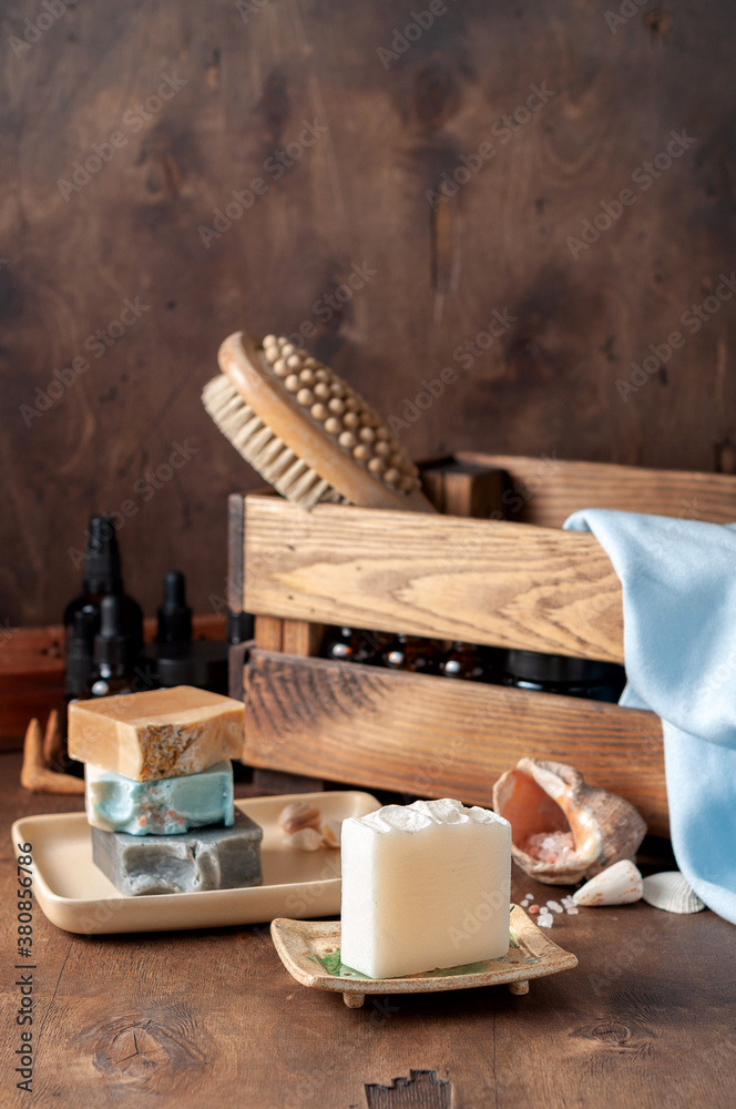 Natural handmade soap bar in ceramic soap dish with spa accessories on wooden table