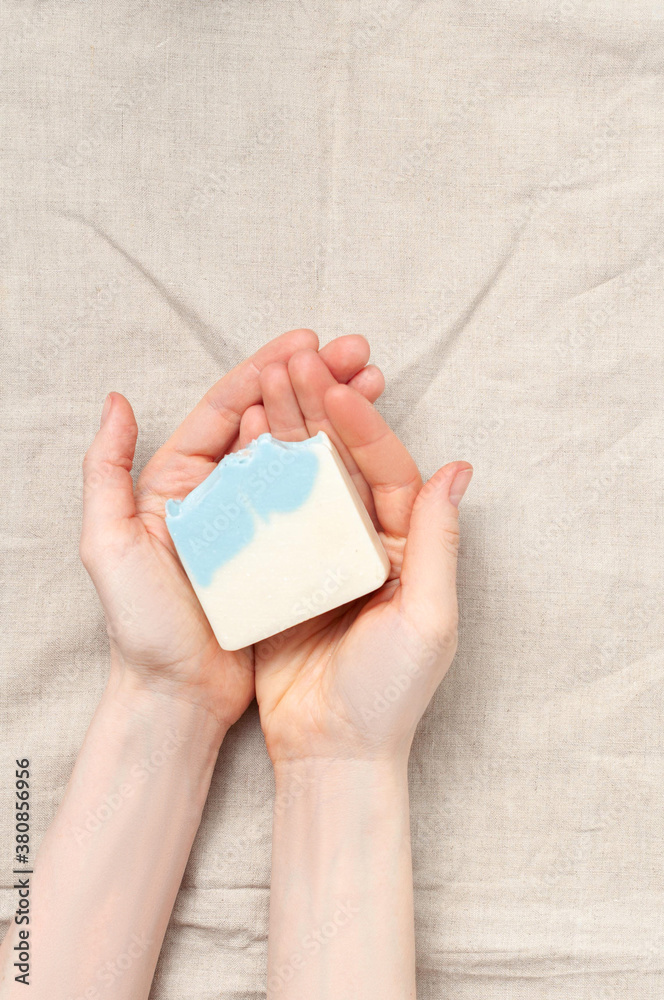 Woman holding natural handmade soap bar on linen fabric background