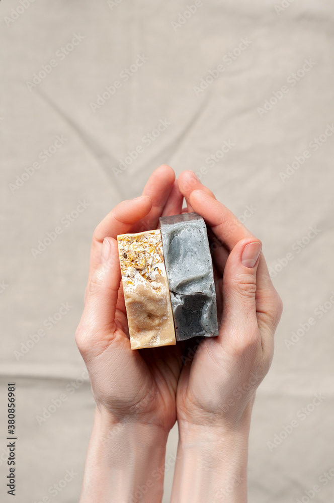 Woman holding natural handmade soap bar on linen fabric background