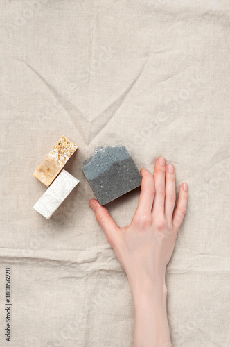 Obraz na płótnie Woman holding natural handmade soap bar on linen fabric background w salonie