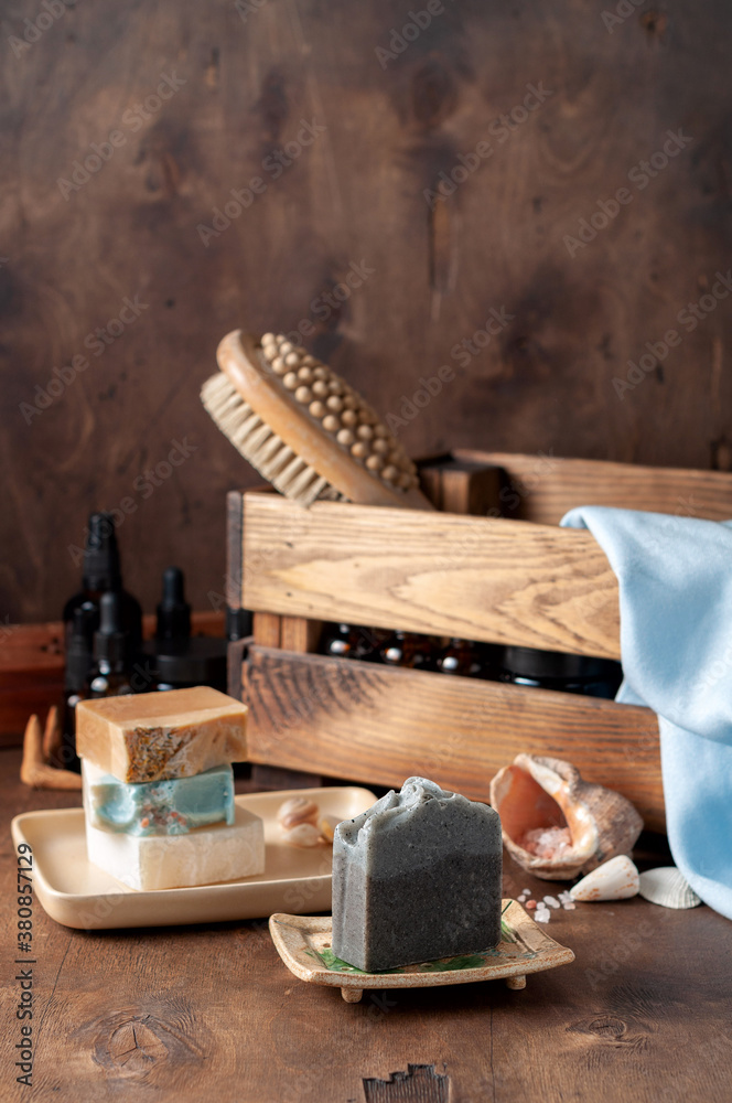 Natural handmade soap bar in ceramic soap dish with spa accessories on wooden table